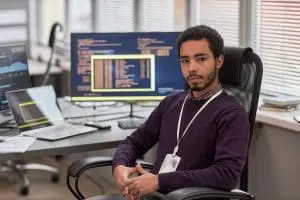 a man sitting at his computer facing us as part of his career in medical coding