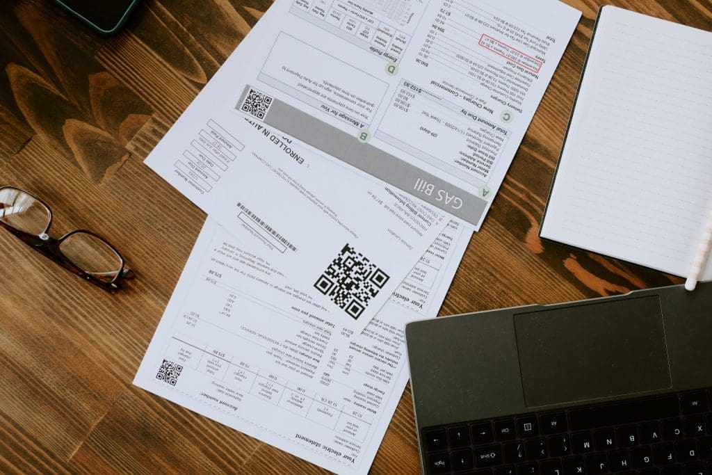 laptop, glasses, and billing invoices on a desk, representing aged receivables support