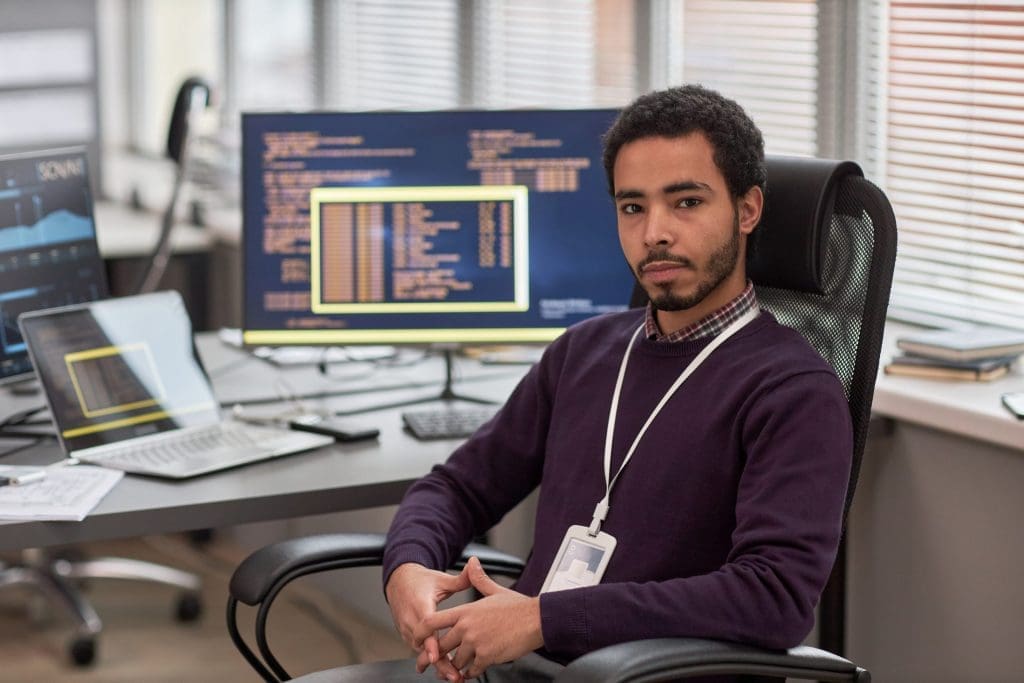 a man sitting at his computer facing us as part of his career in medical coding